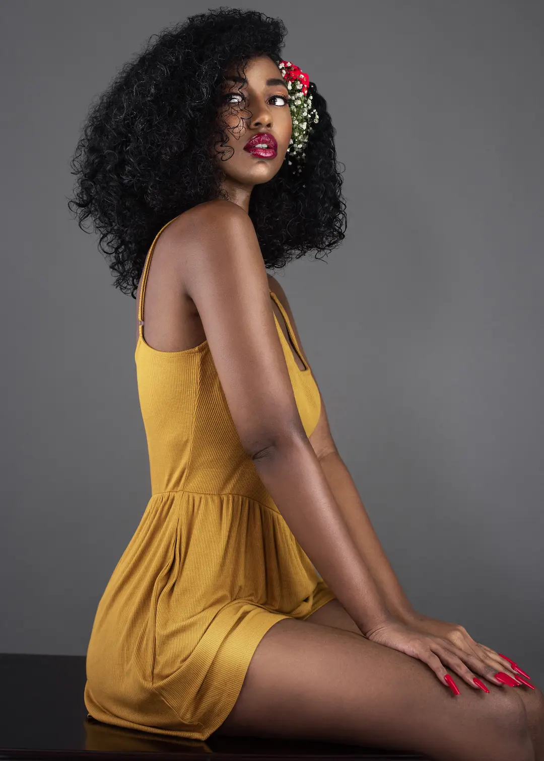 Black model in a yellow dress with flowers woven into long natural curls